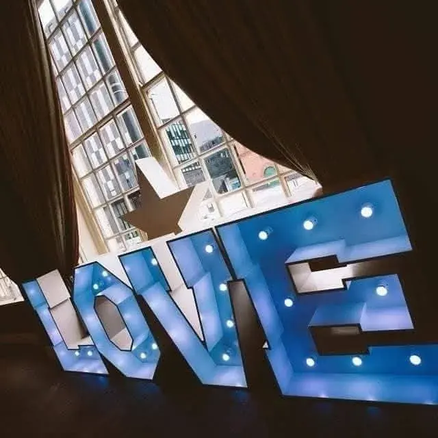 White LOVE letters illuminated in blue in front of tall windows