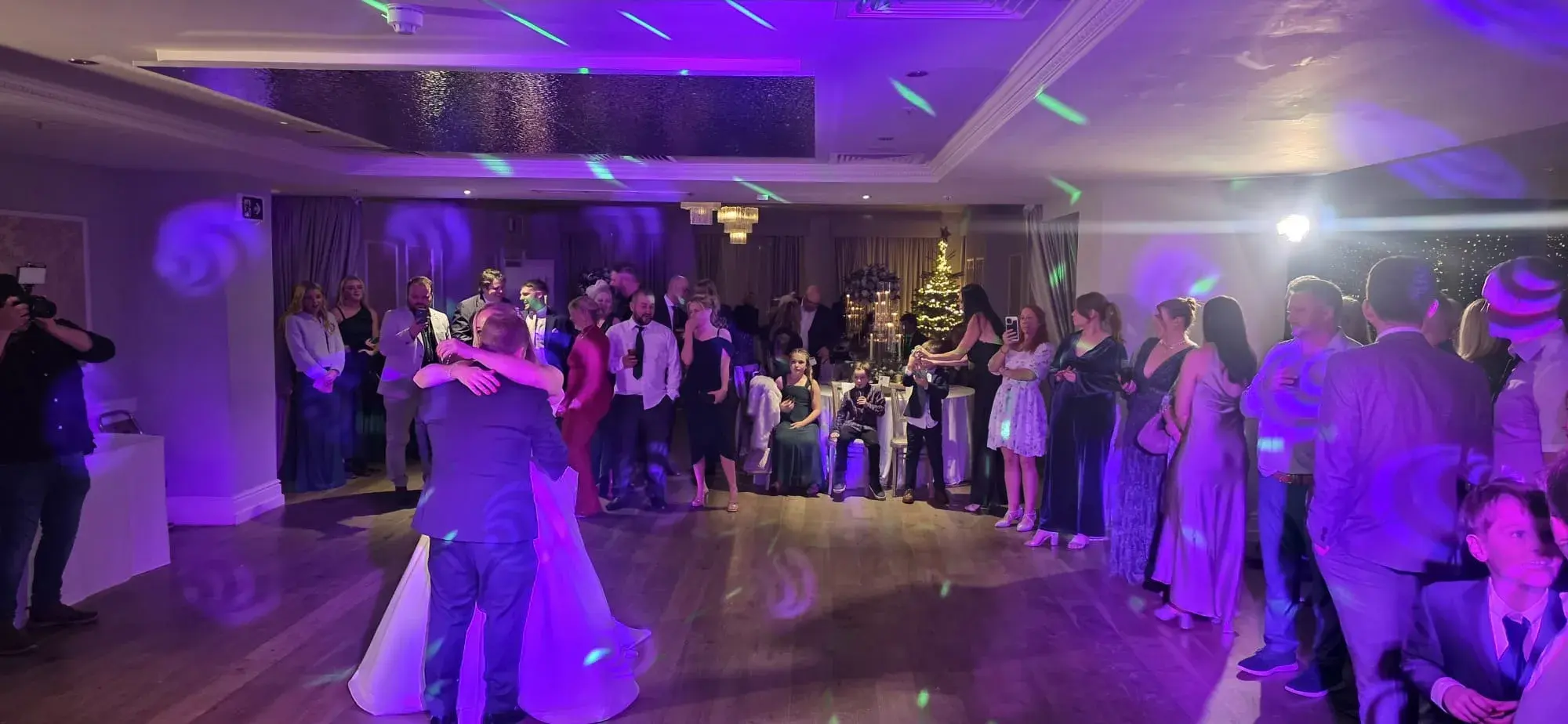 A wedding couple dancing with guests gathered around the dance floor