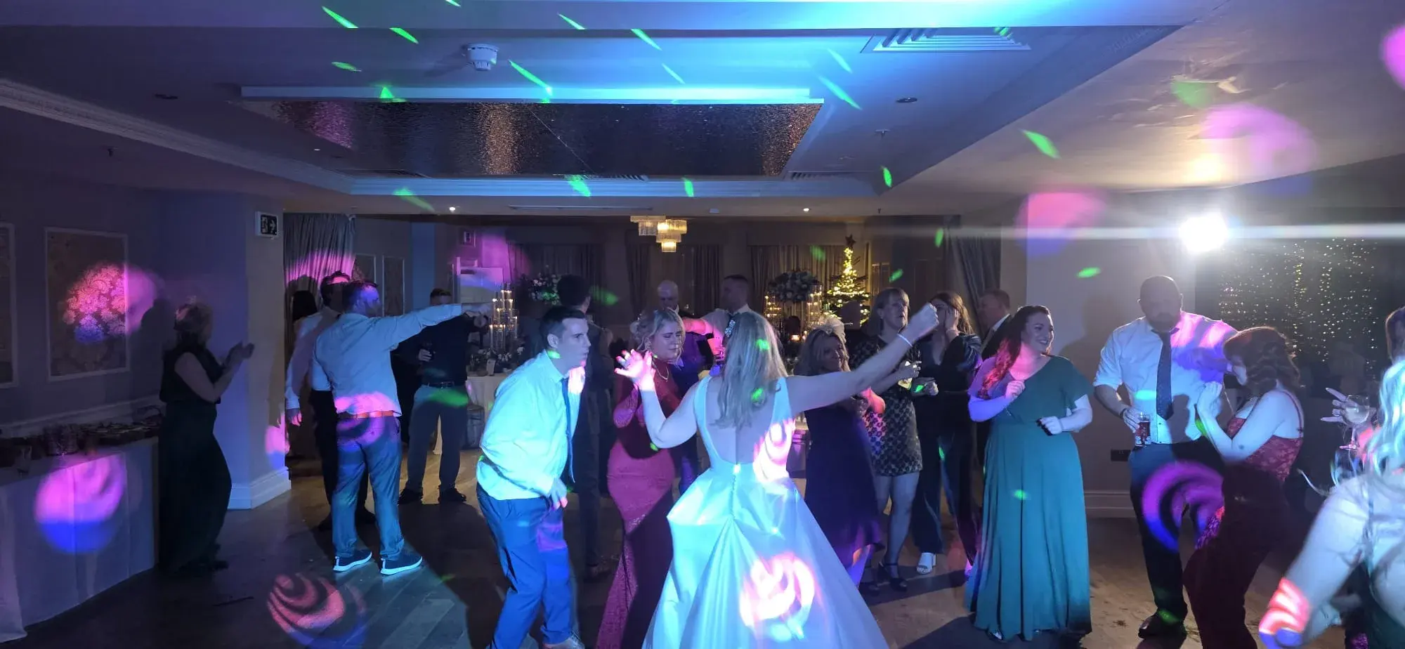 A bride and wedding guests dancing under colourful disco lighting